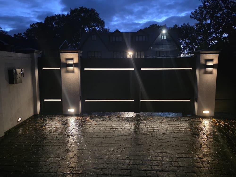 Black contemporary double swing gates with LED lighting at night