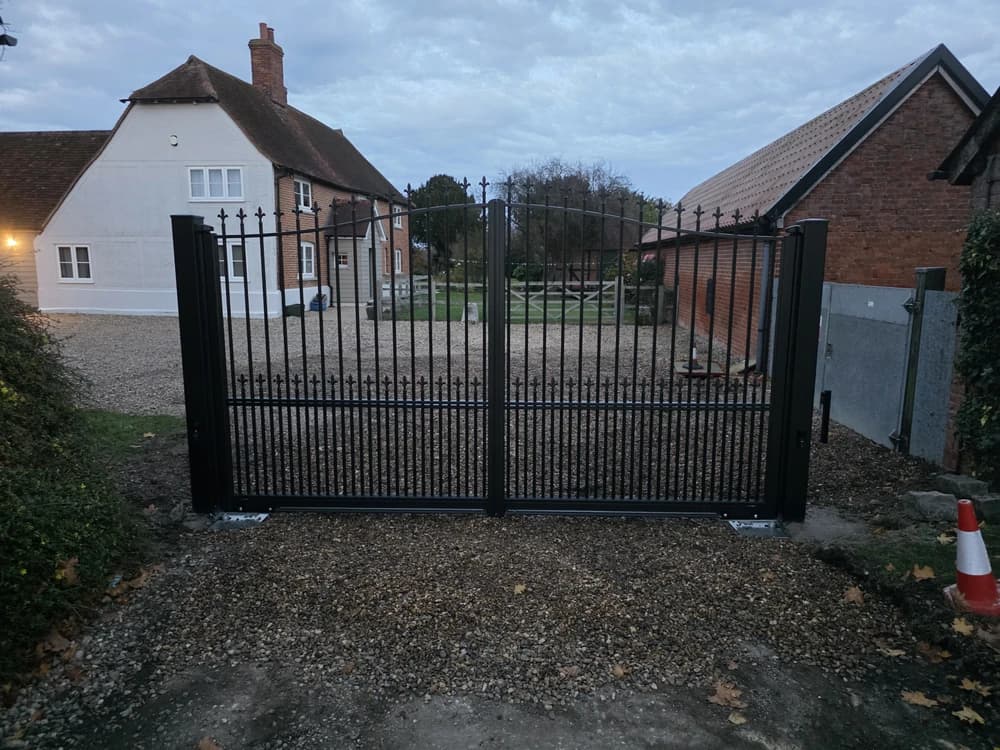Black metal bow-top double swing gates photographed at dusk