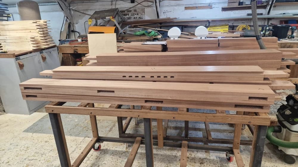 Machined hardwood stiles with cut mortises on the bench